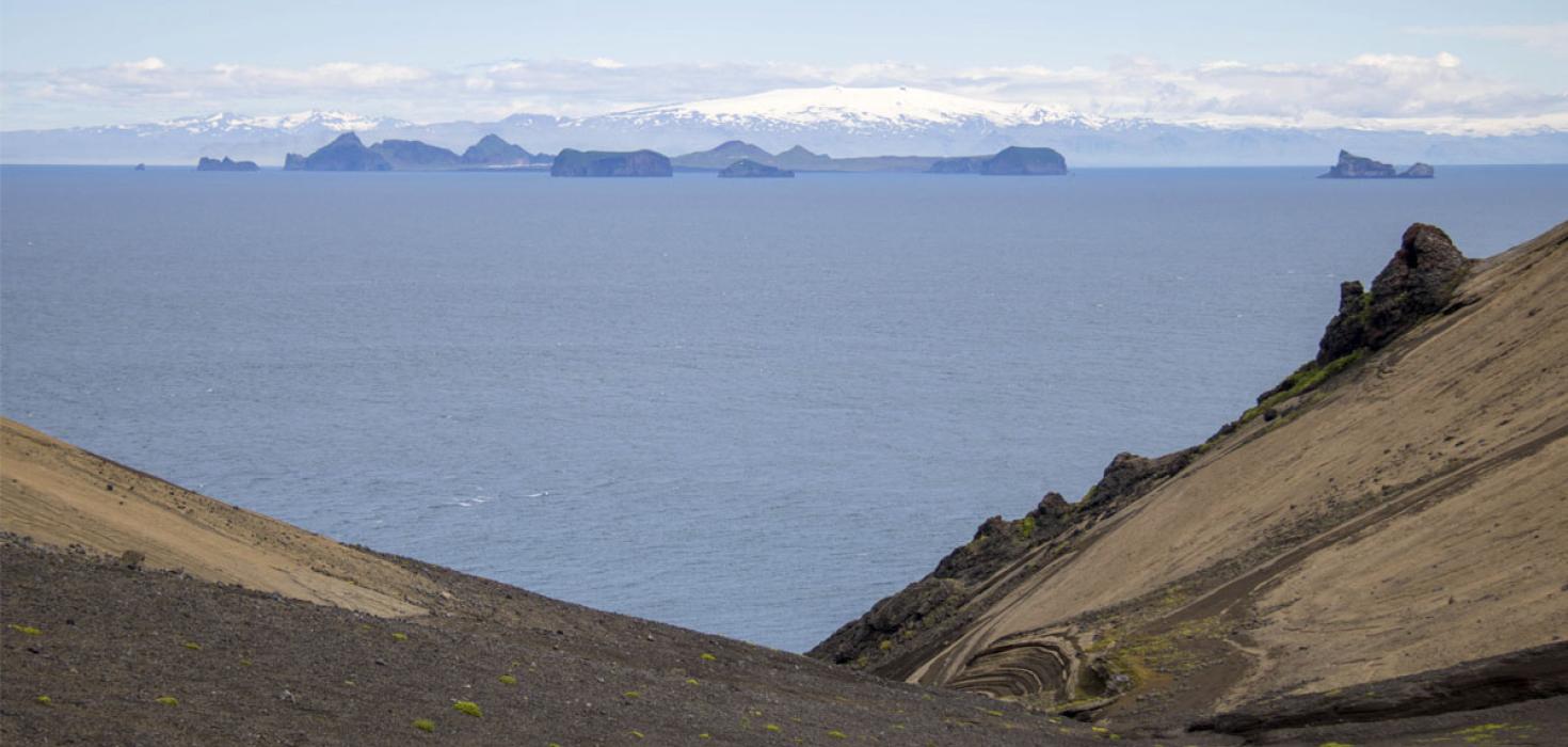 Frá Surtsey. Landsýn úr Svartagili til Vestmannaeyja á fögrum degi, í bakgrunni Tindfjöll og Eyjafjallajökull. Smágígurinn Strompur til hægri. 